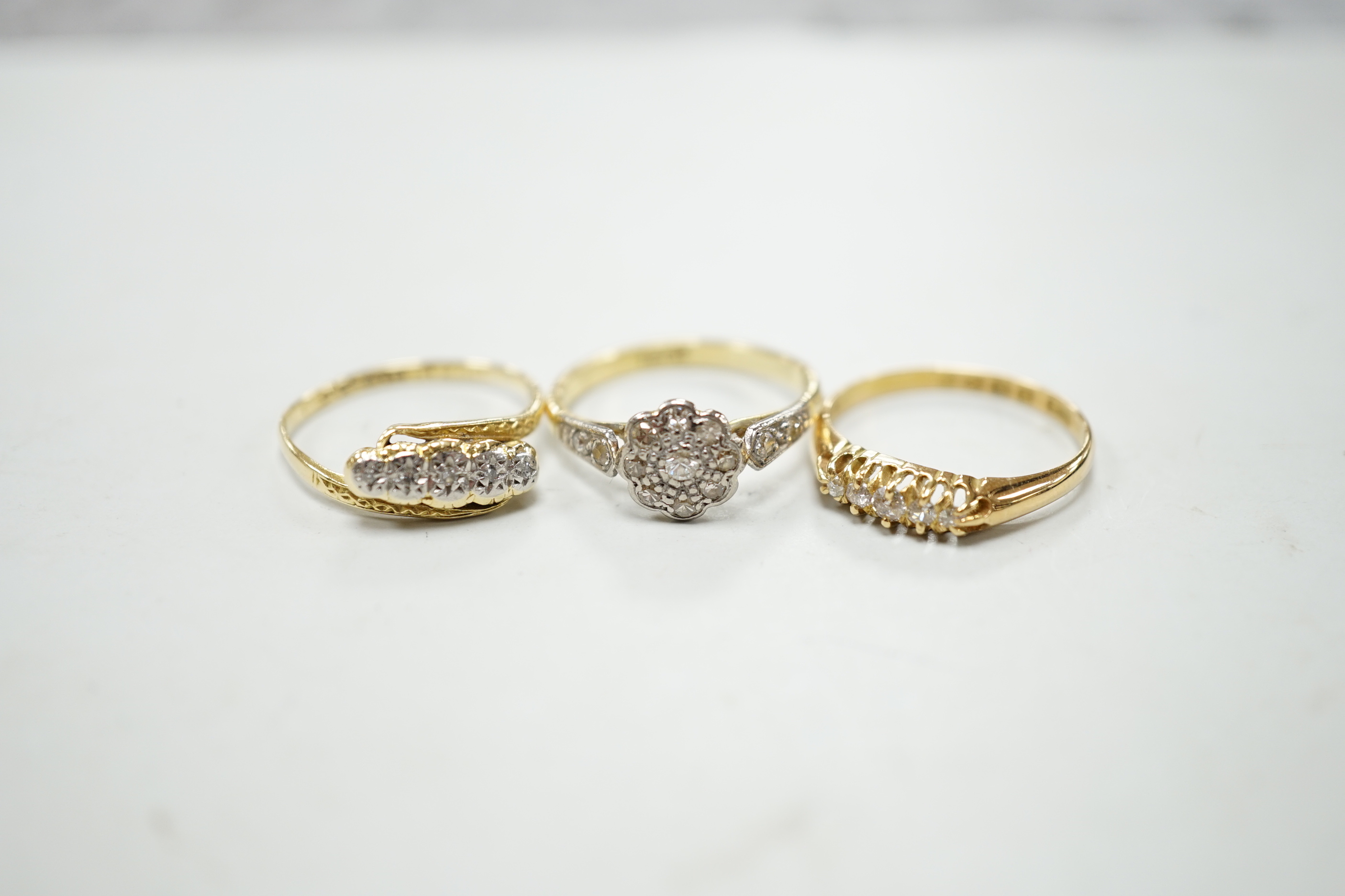 Three assorted 18ct and diamond cluster set rings including a late Victorian five stone diamond chip half hoop, gross weight 7.9 grams.